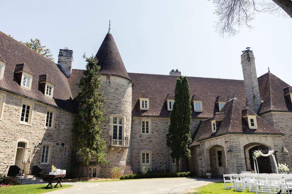 A grand stone castle-like manor with turrets and chimneys features elegant French architecture and manicured grounds.