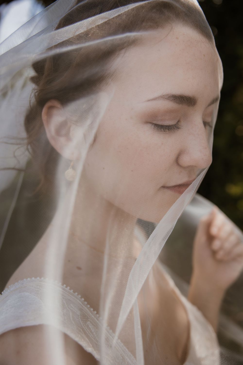 Close up portrait of a bride wearing a delicate veil in a dreamy, serene moment at Meadowbrook Park in Prairie Village Kansas.