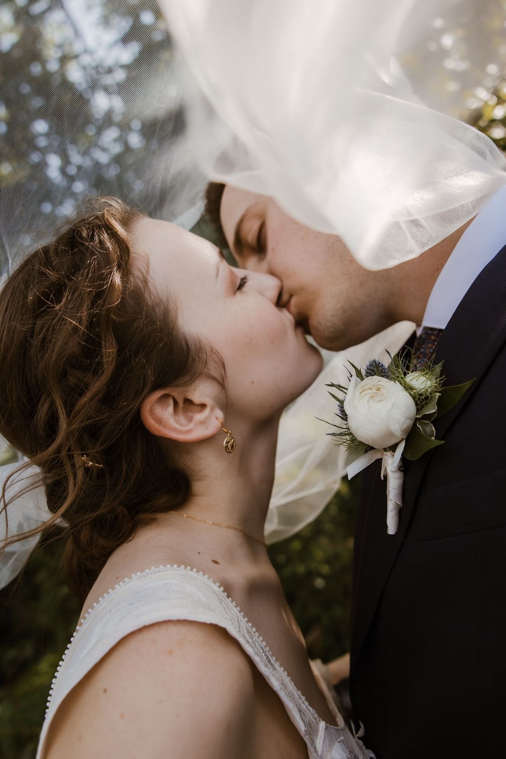 Kansas City wedding couple sharing a kiss under the trees at Meadowbrook Park after their church ceremony in Prairie Village.