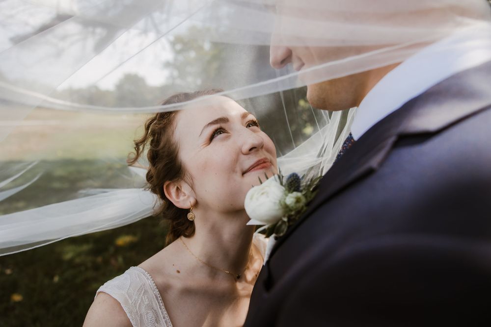 Bride’s veil floating in the breeze during romantic Meadowbrook Park portraits with her groom at their Kansas City summer wedding.