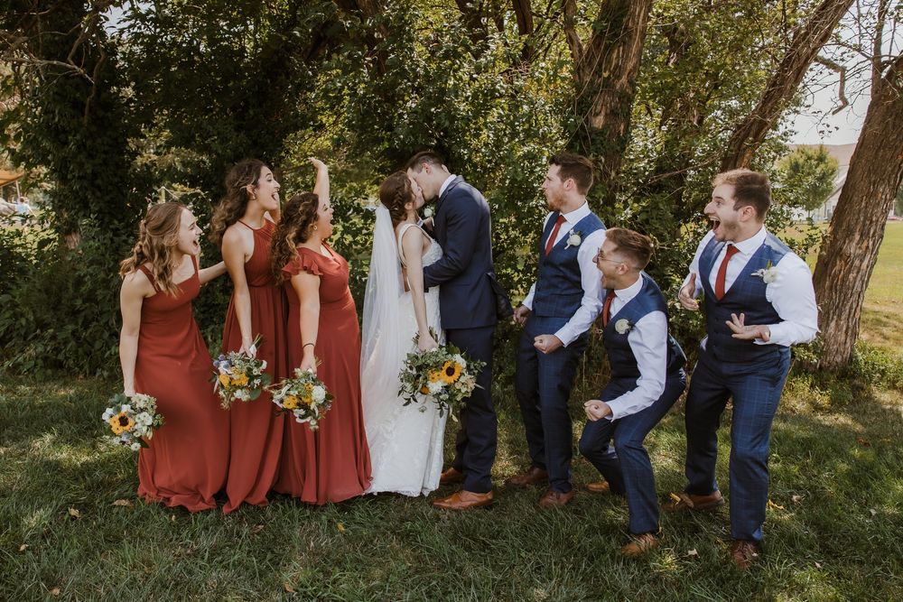 Rust and navy bridal party poses for wedding portraits at Meadowbrook Park in Prairie Village, Kansas with sunflowers and greenery bouquets.
