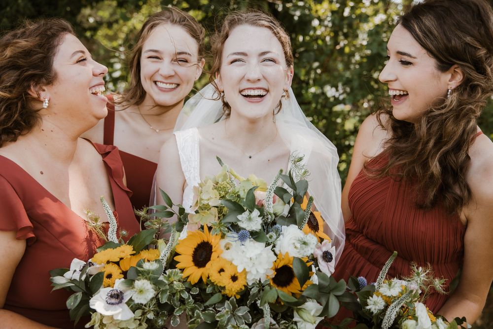 Kansas City wedding bridal party laughing together during group photos at Meadowbrook Park on a sunny summer wedding day.