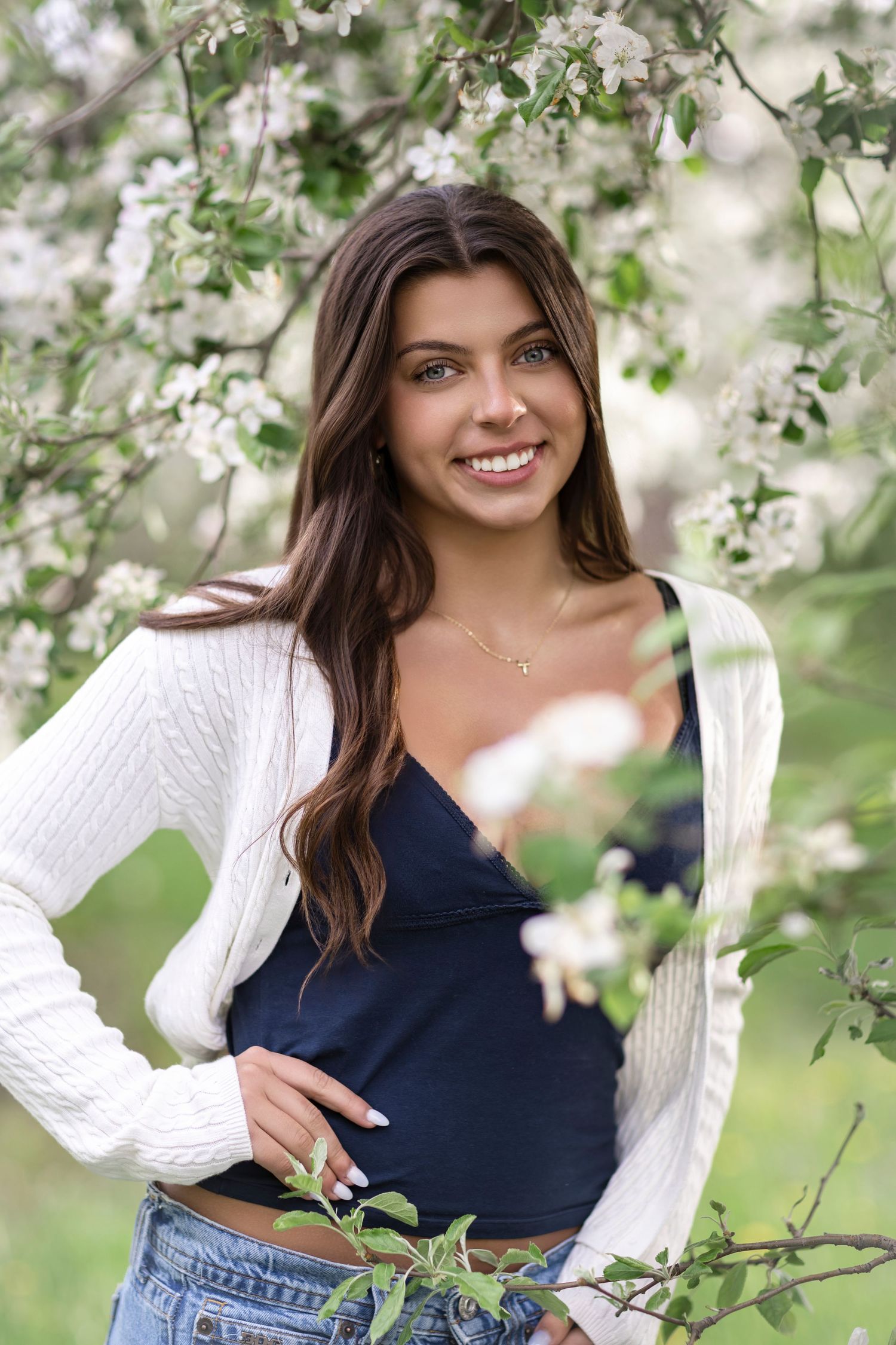 Senior girl walking through orchard rows during spring photoshoot in Allegan County, Michigan