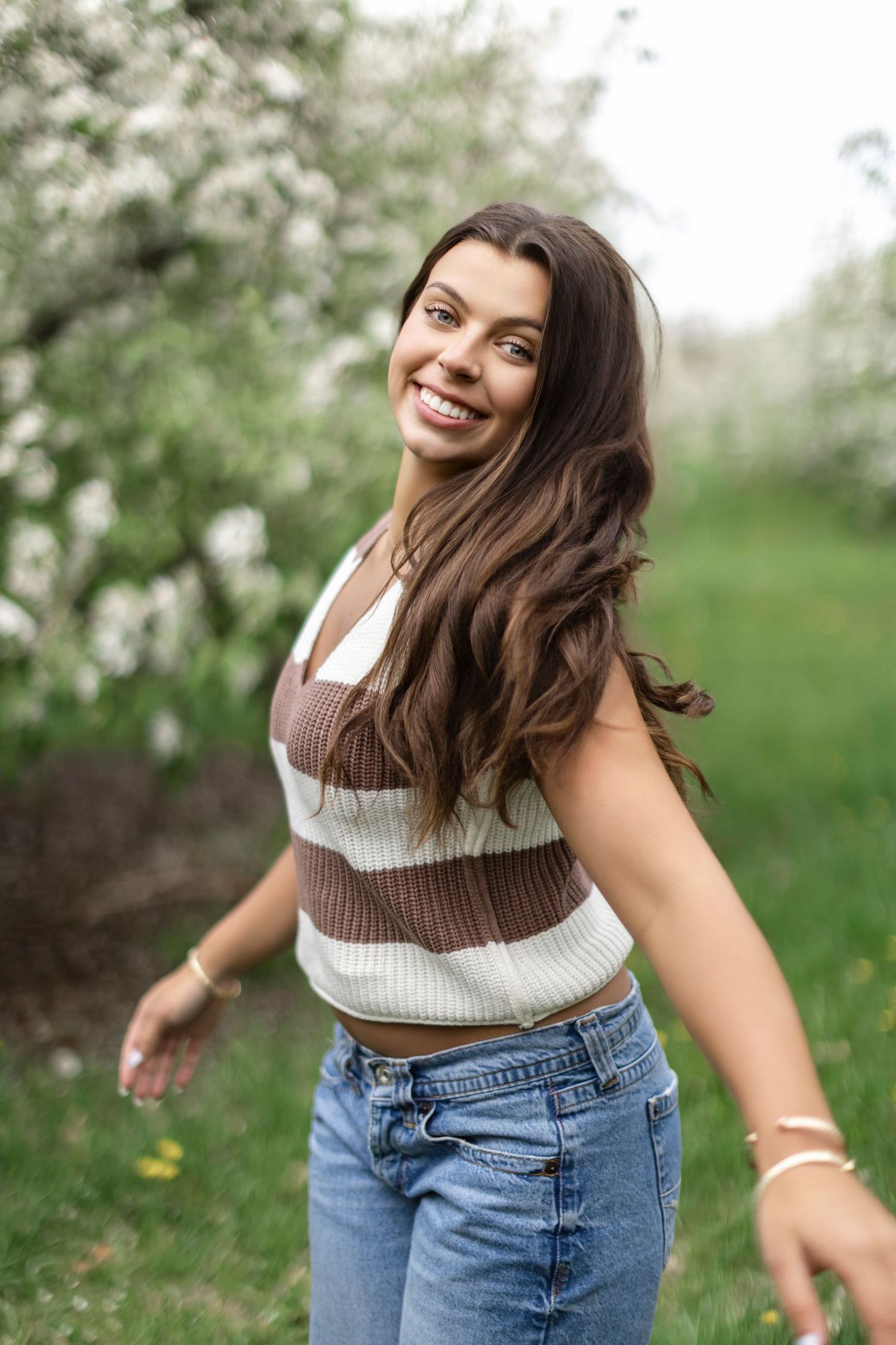 Natural light senior photo in a blooming orchard in Allegan County, MI with soft floral tones