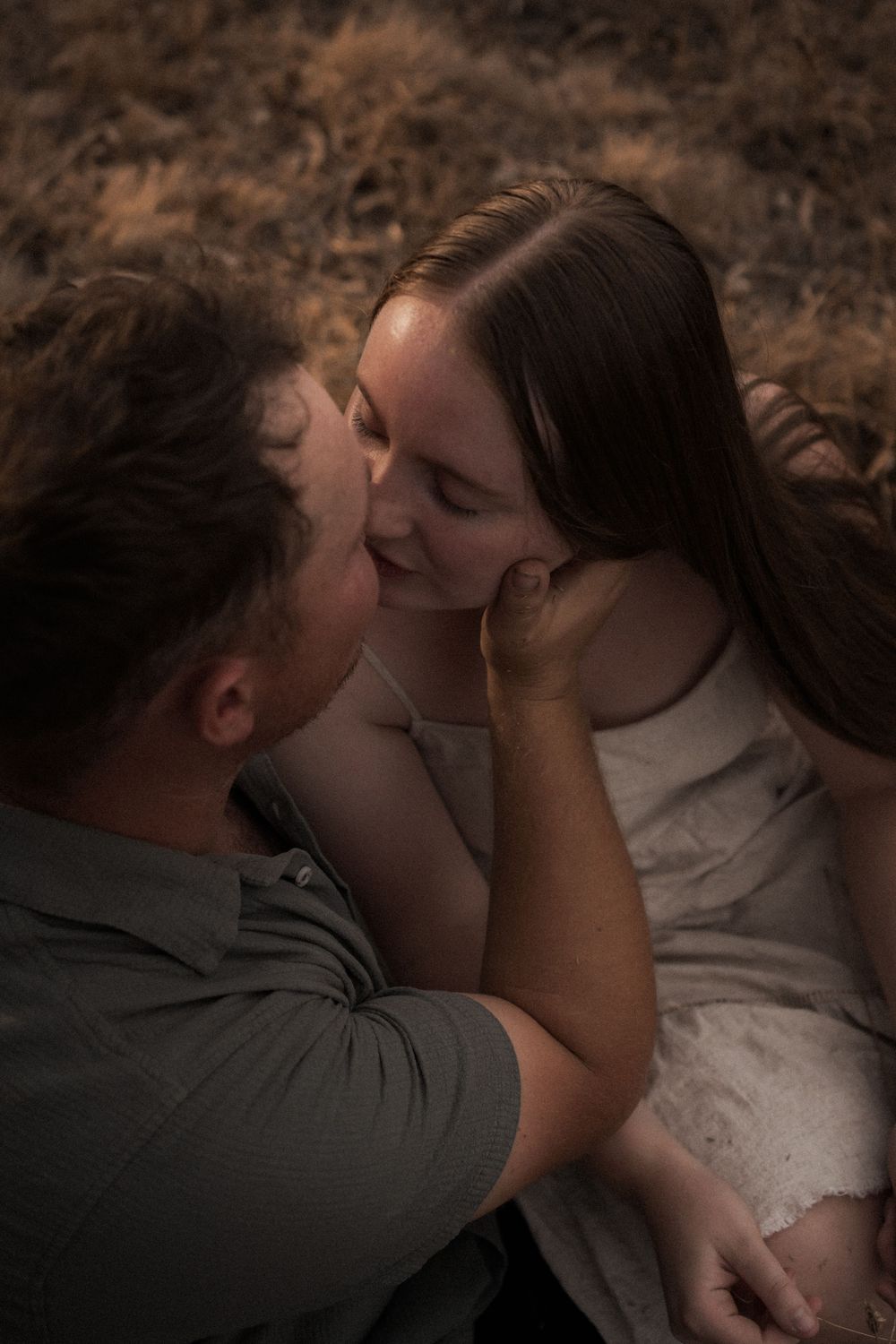 A romantic couple shares an intimate moment outdoors in soft, moody lighting during a lifestyle photoshoot.