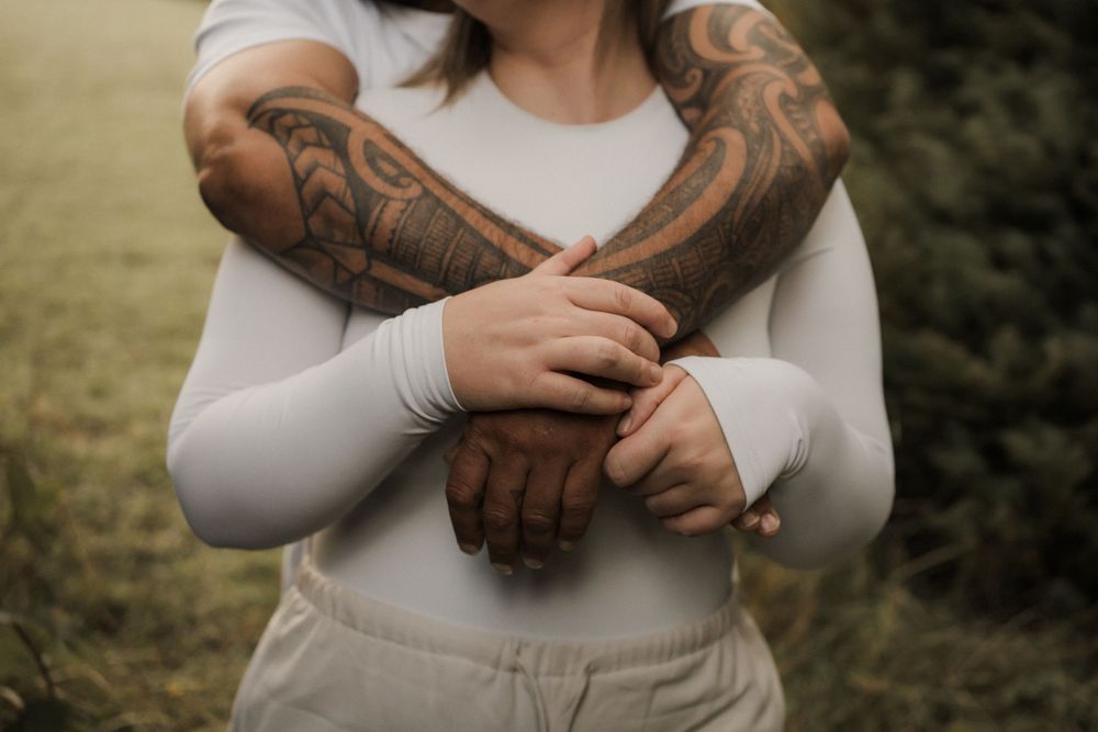 Someone with heavily tattooed arms and hands adjusts their white long-sleeved shirt in a series of close-up shots.