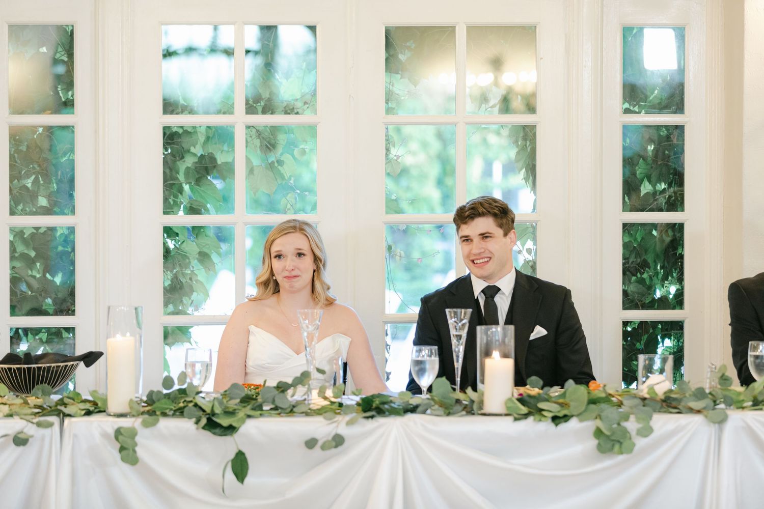 A tender black and white wedding photo of a couple sharing an intimate moment outdoors in a park setting.