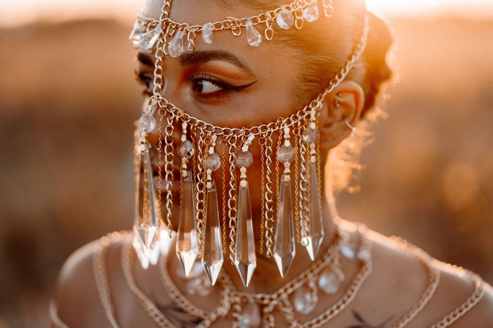 Ornate silver bridal jewelry with cascading crystal details catches golden sunlight in an ethereal close-up shot.