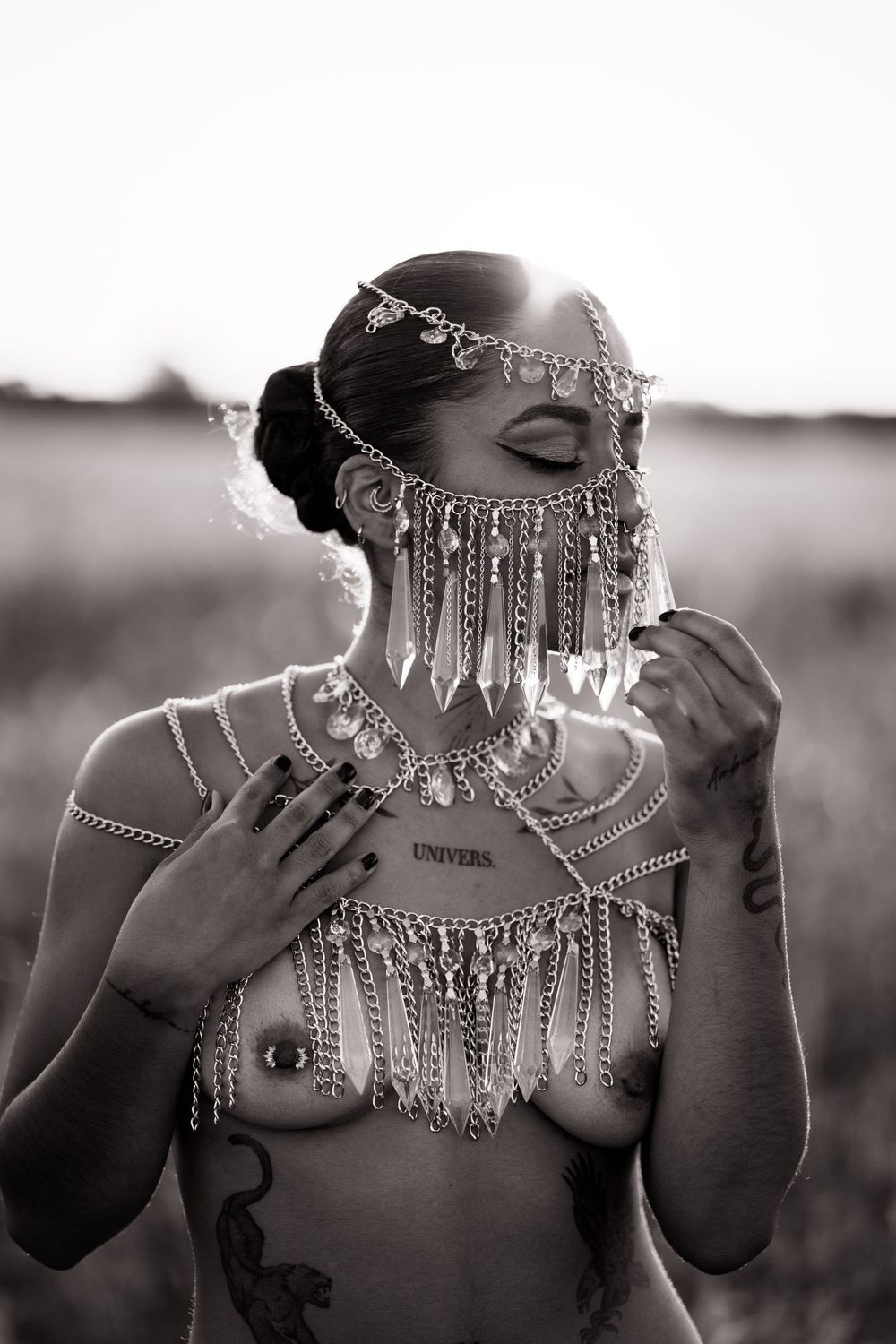 Artistic black and white photo showing an ornate silver chain headdress and necklace with dangling metallic details.