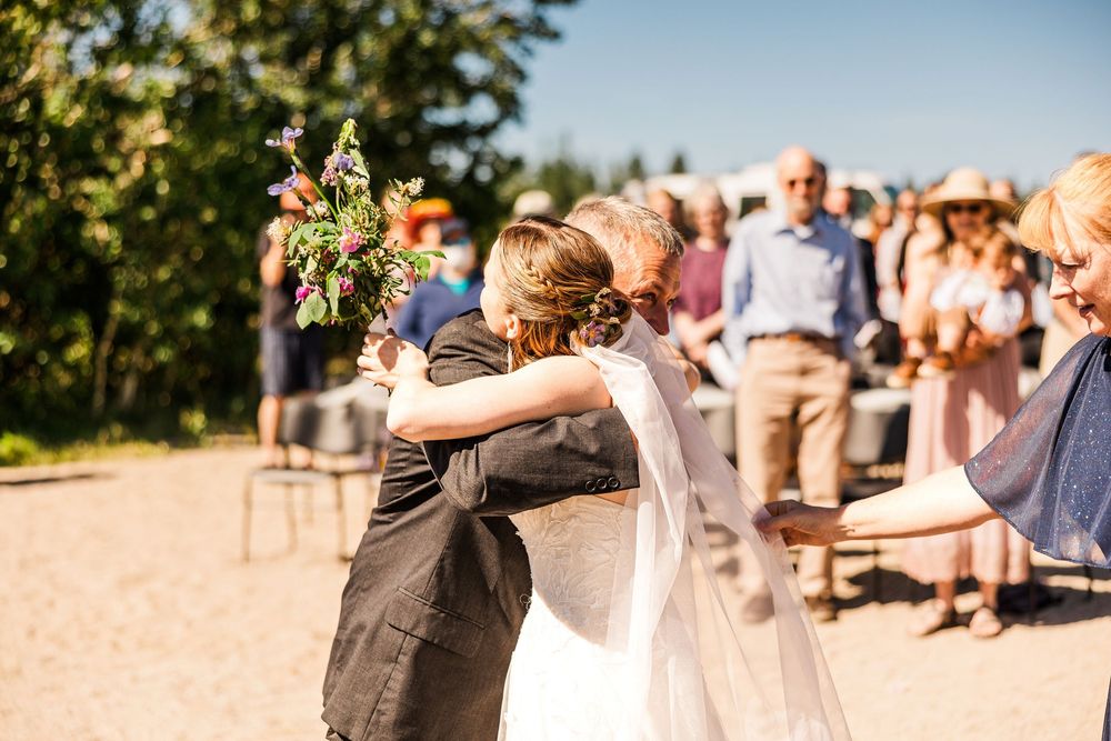 Couple shares passionate kiss during outdoor wedding ceremony as guests look on.