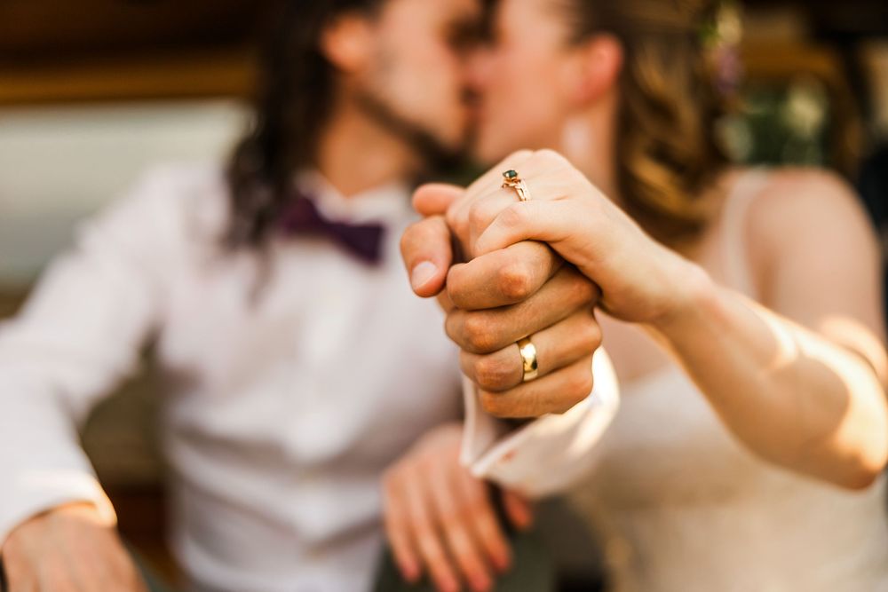 Close-up shot of clasped hands showing wedding rings and romantic details.