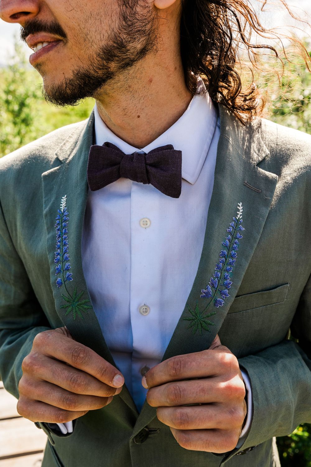 Close-up of embroidered blue floral details on grey suit jacket.