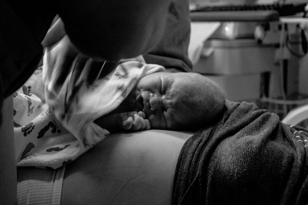 A black and white close-up photograph of a newborn baby laying on their mother's chest..