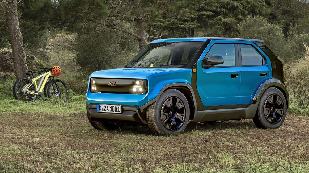 A bright blue Opel Rocks Electric compact SUV parked on dirt terrain with a bicycle in the background.