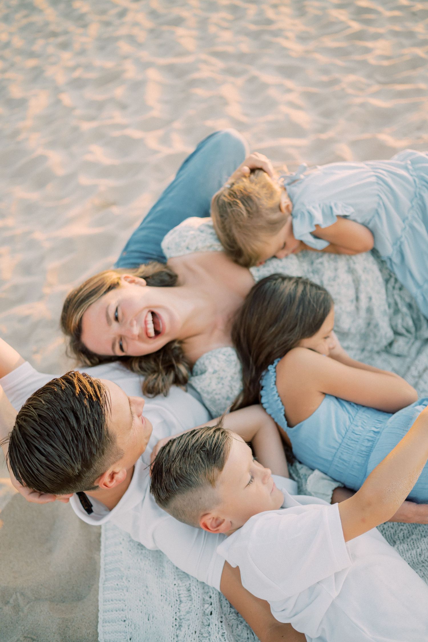 Family lying together on beach sand sharing laughter and joy.