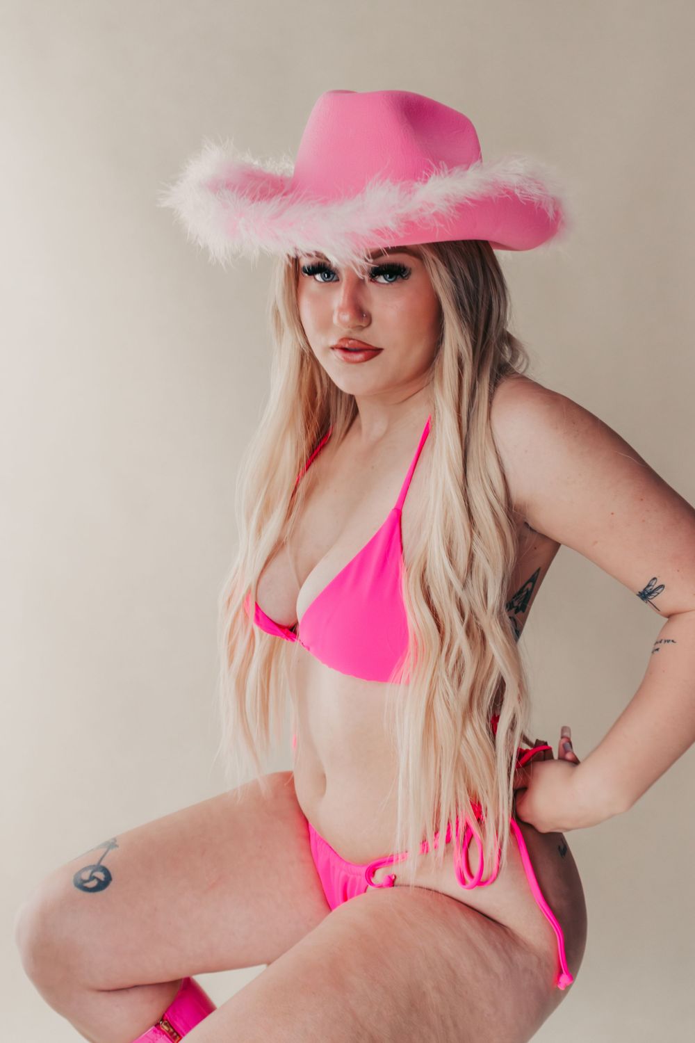 Studio Boudoir Photoshoot
Model in bright pink bikini and fluffy-trimmed cowgirl hat poses against neutral backdrop.