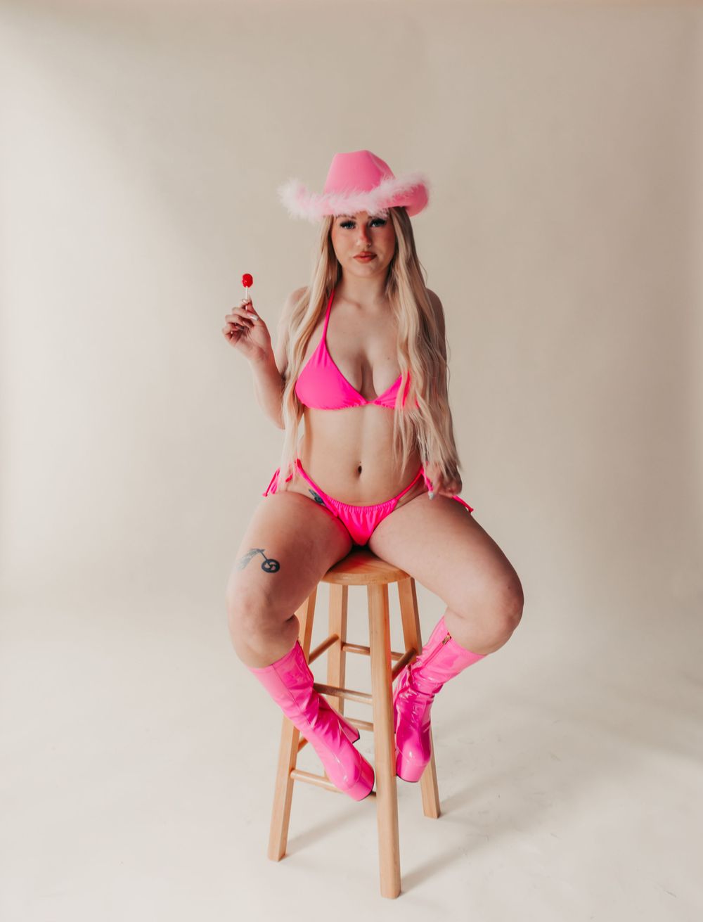 Studio Boudoir Photoshoot
Woman in hot pink bikini and matching cowboy hat poses on wooden stool in boudoir photoshoot.