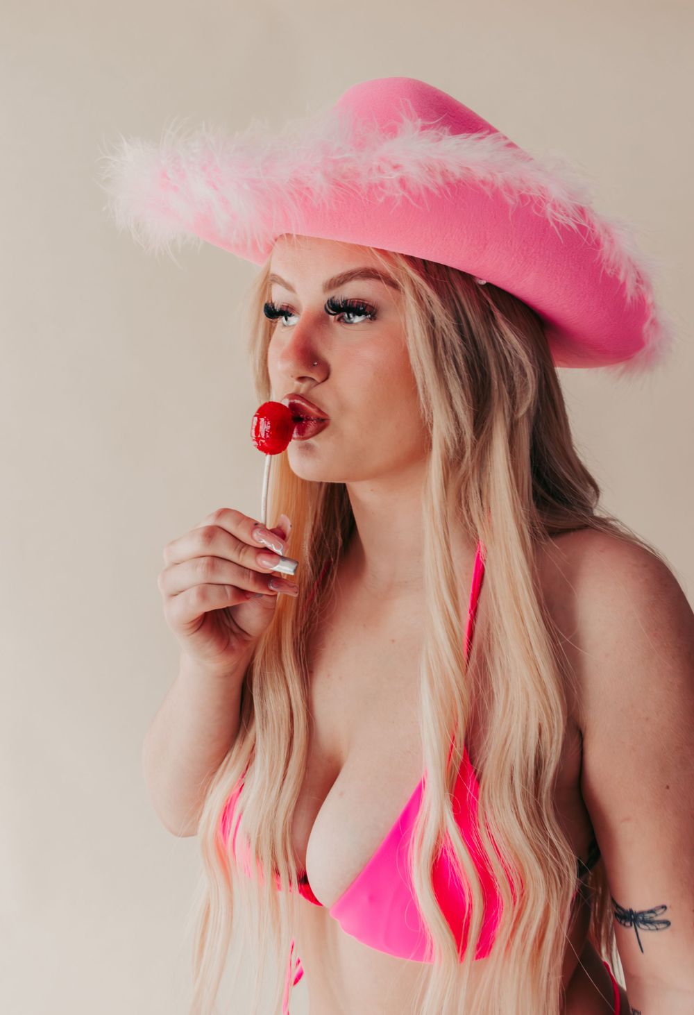 Studio Boudoir Photoshoot
Fashion portrait with pink cowboy hat, pink bikini top, and red lollipop against neutral background.