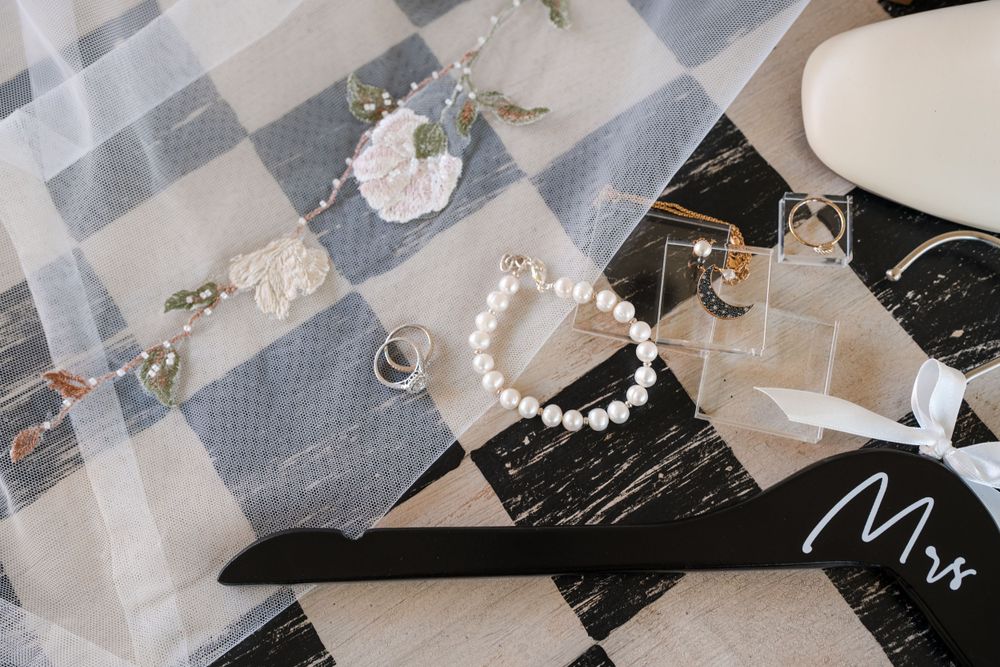 Wedding accessories including pearl necklace and veil arranged on marble surface.