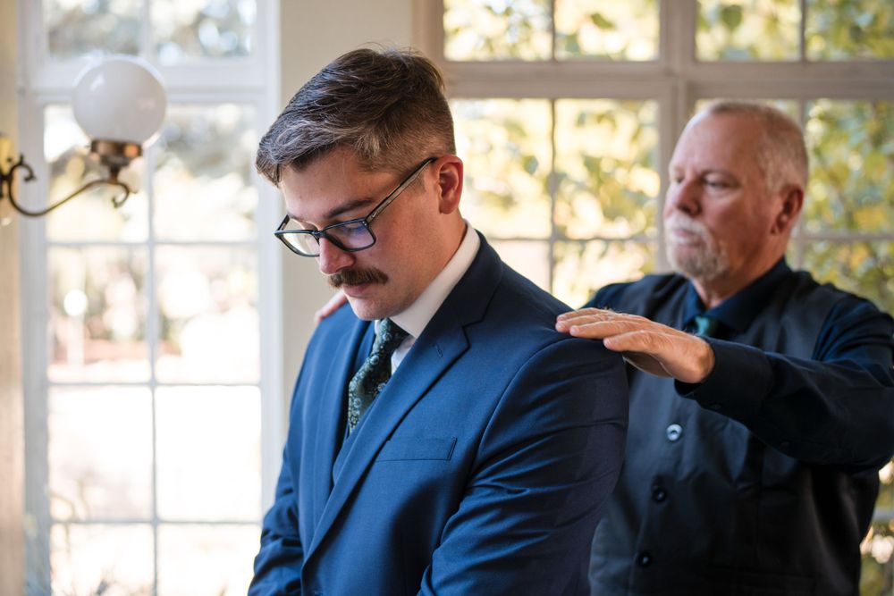Two people sharing a pre-wedding preparation moment in formal attire.