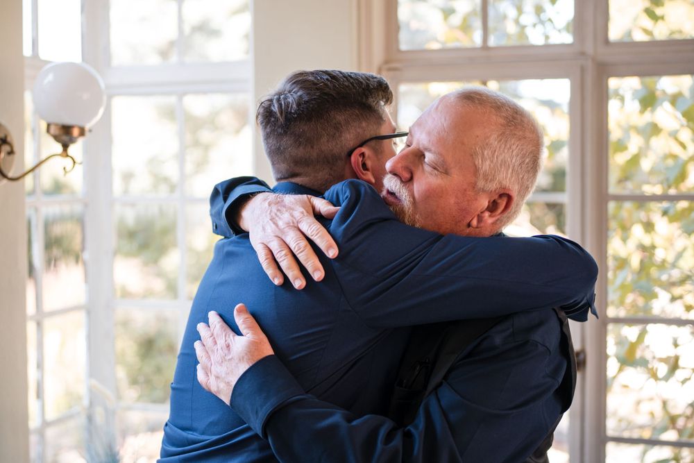 Two people share an emotional embrace in a bright sunlit room.