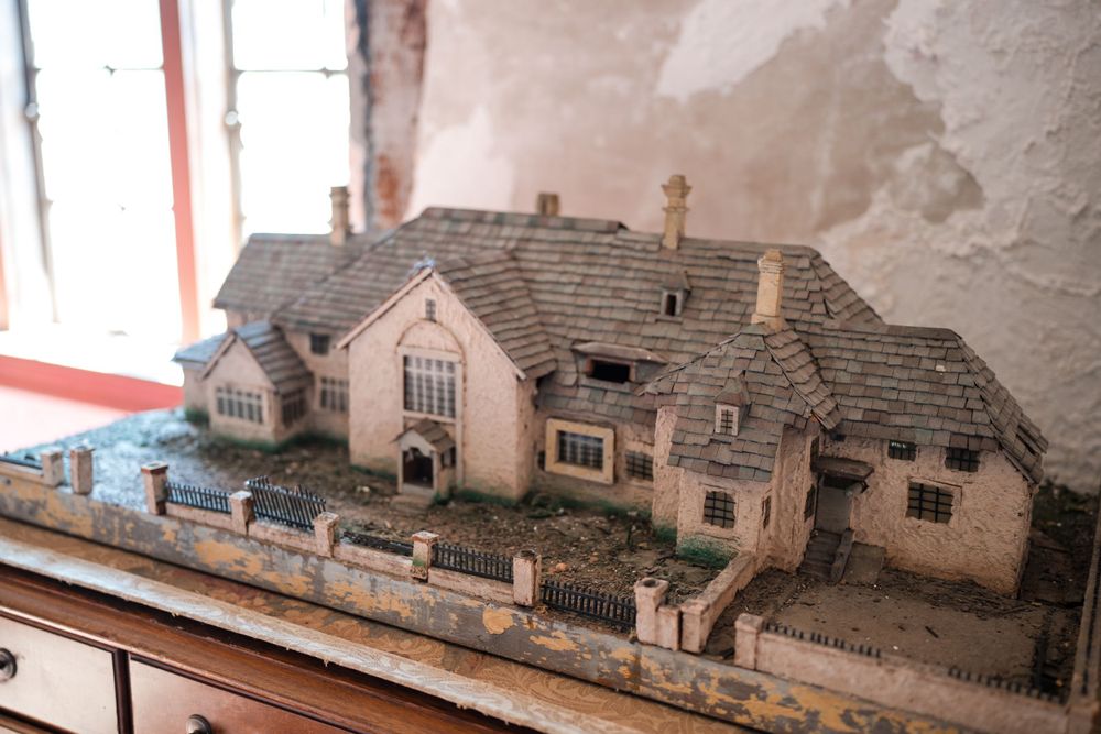 Detailed miniature model of connected Tudor-style houses with small fences and gardens.