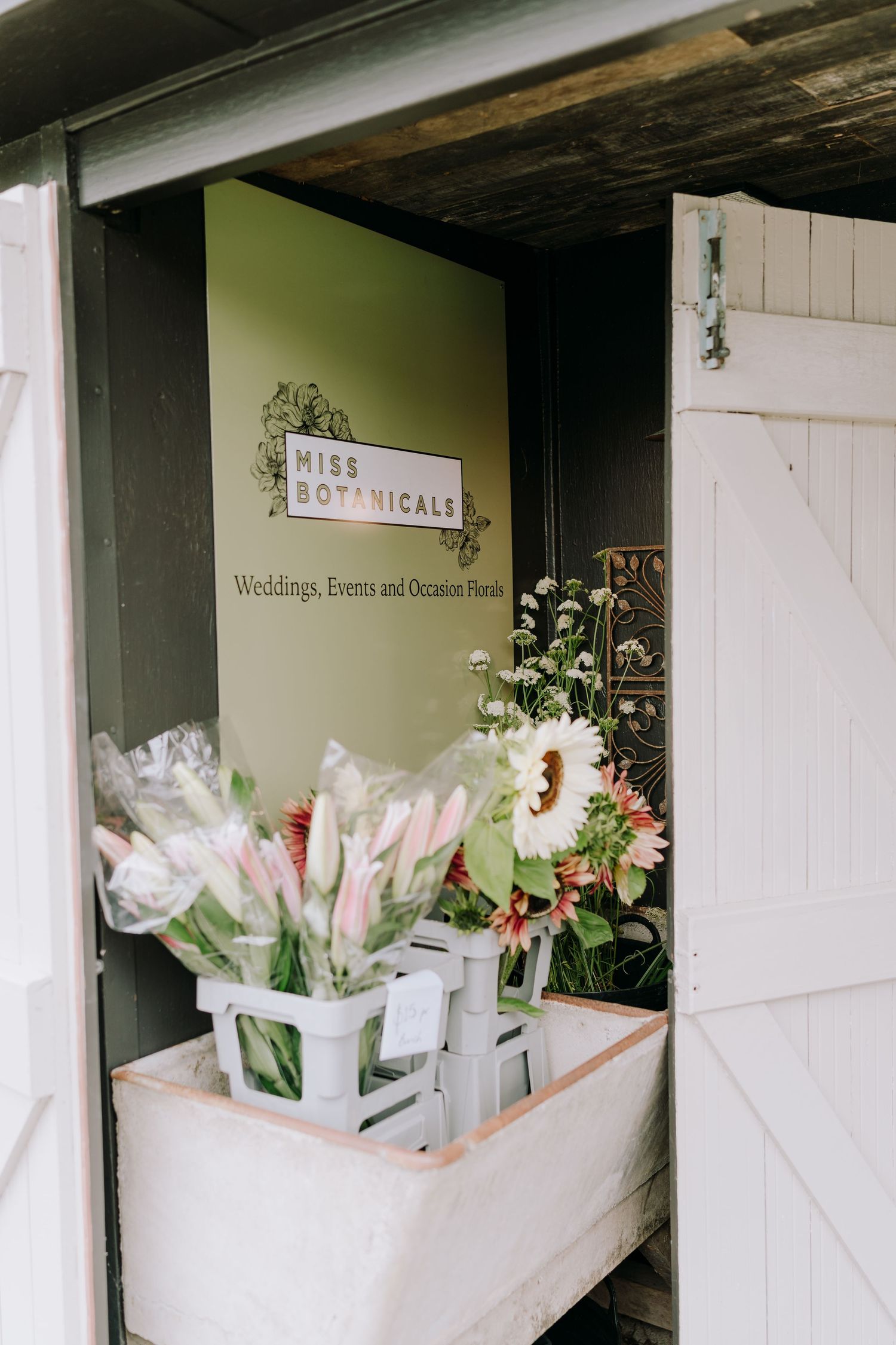 A florist shop entrance with white door and fresh flower arrangements on display.