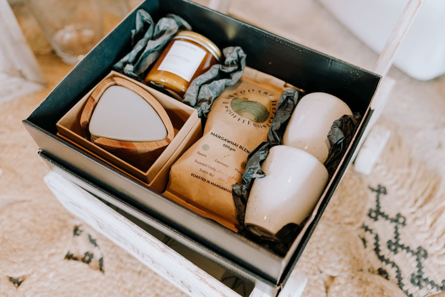 A gift box containing carefully packaged coffee and ceramic mugs.