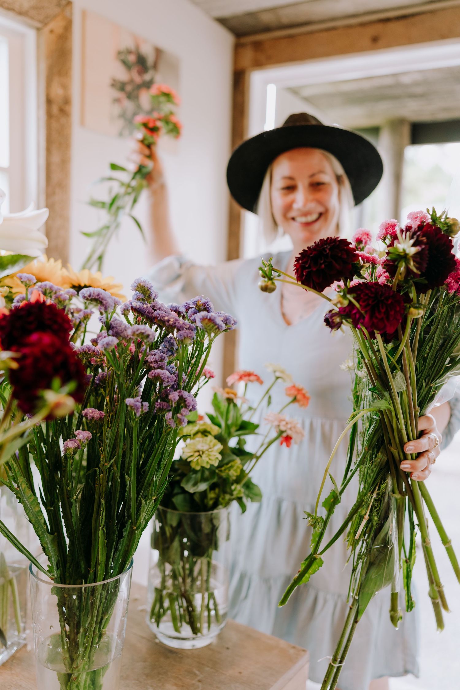 A florist wearing a black hat working with vibrant flower arrangements in a bright workspace.