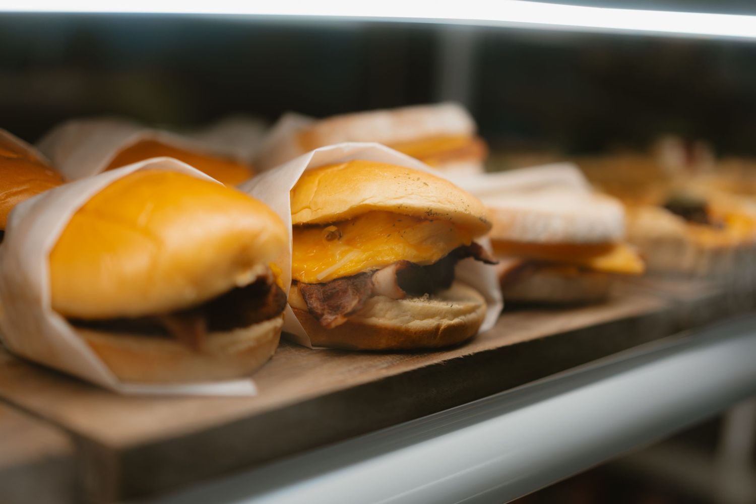 Row of wrapped sandwiches displayed on dark serving tray in restaurant setting.