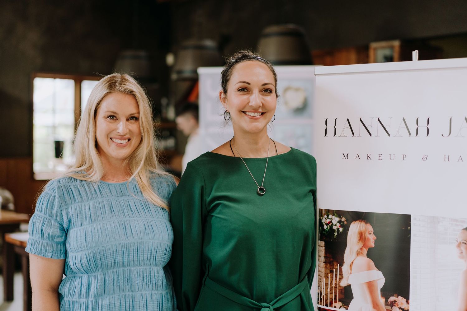 Two people standing together at a beauty event with business signage.