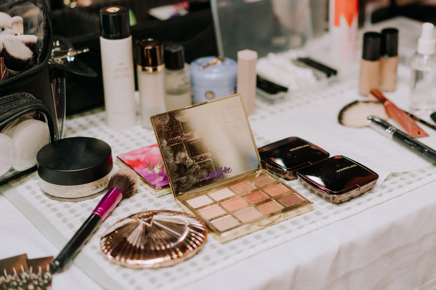 Various makeup and beauty products arranged on a white table with photographs.