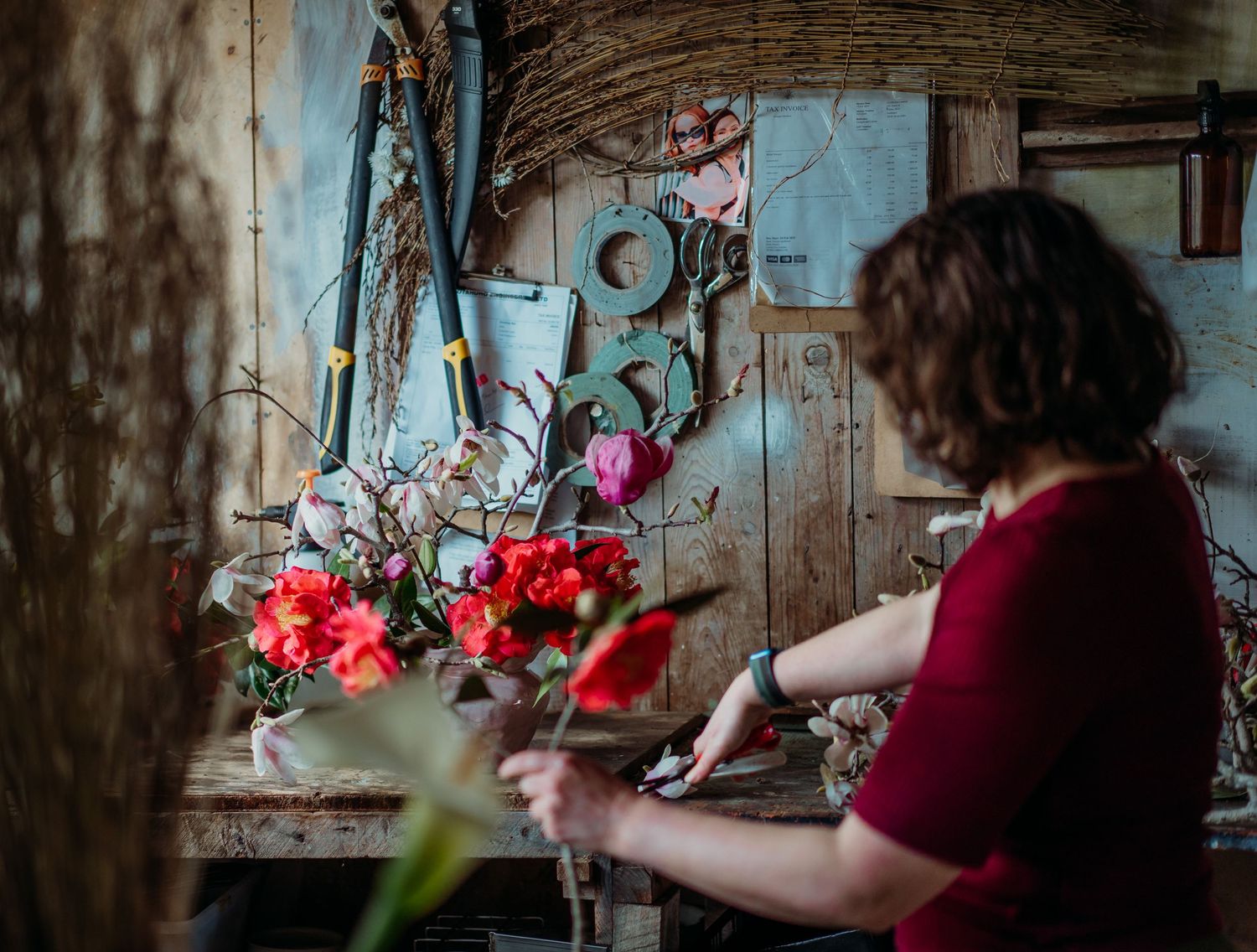 Floral arrangement being created with vibrant red blooms against a rustic background.