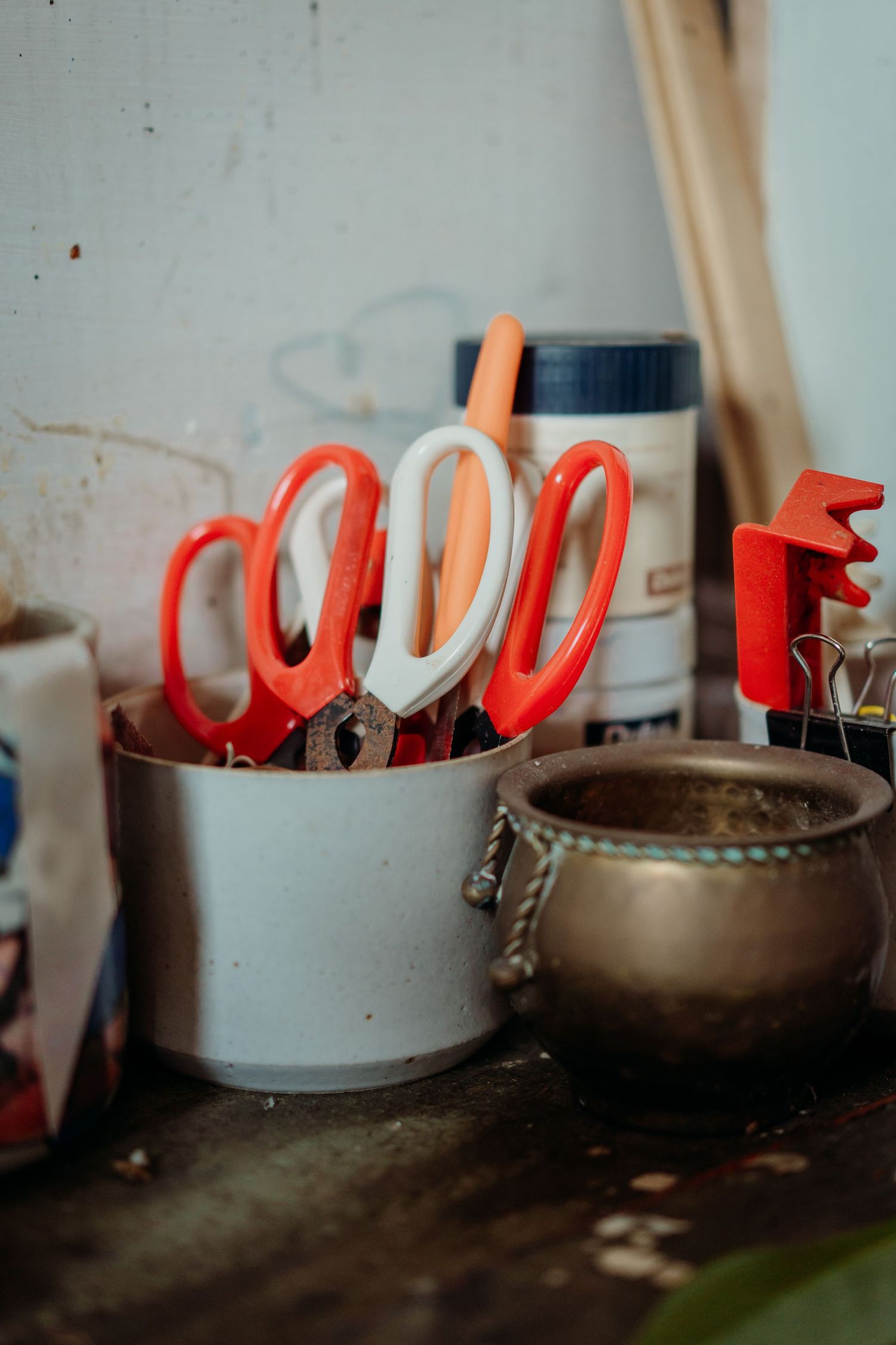 Red and white scissors arranged in a metal container alongside other craft supplies.