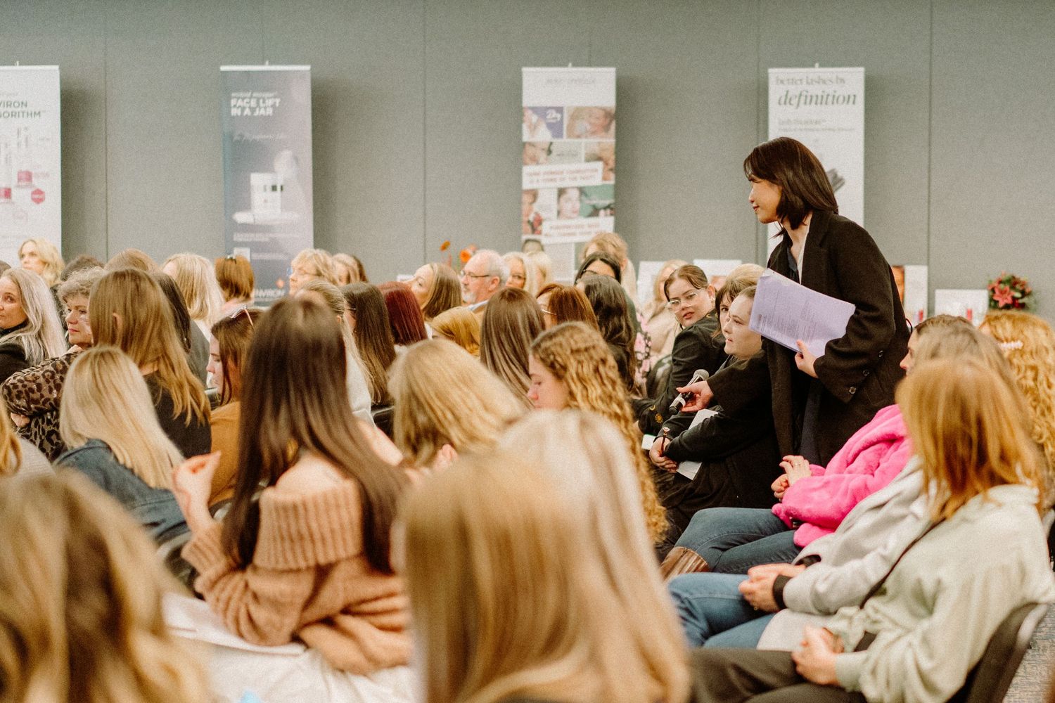 Crowded seminar room with attendees seated in rows listening to a presentation.