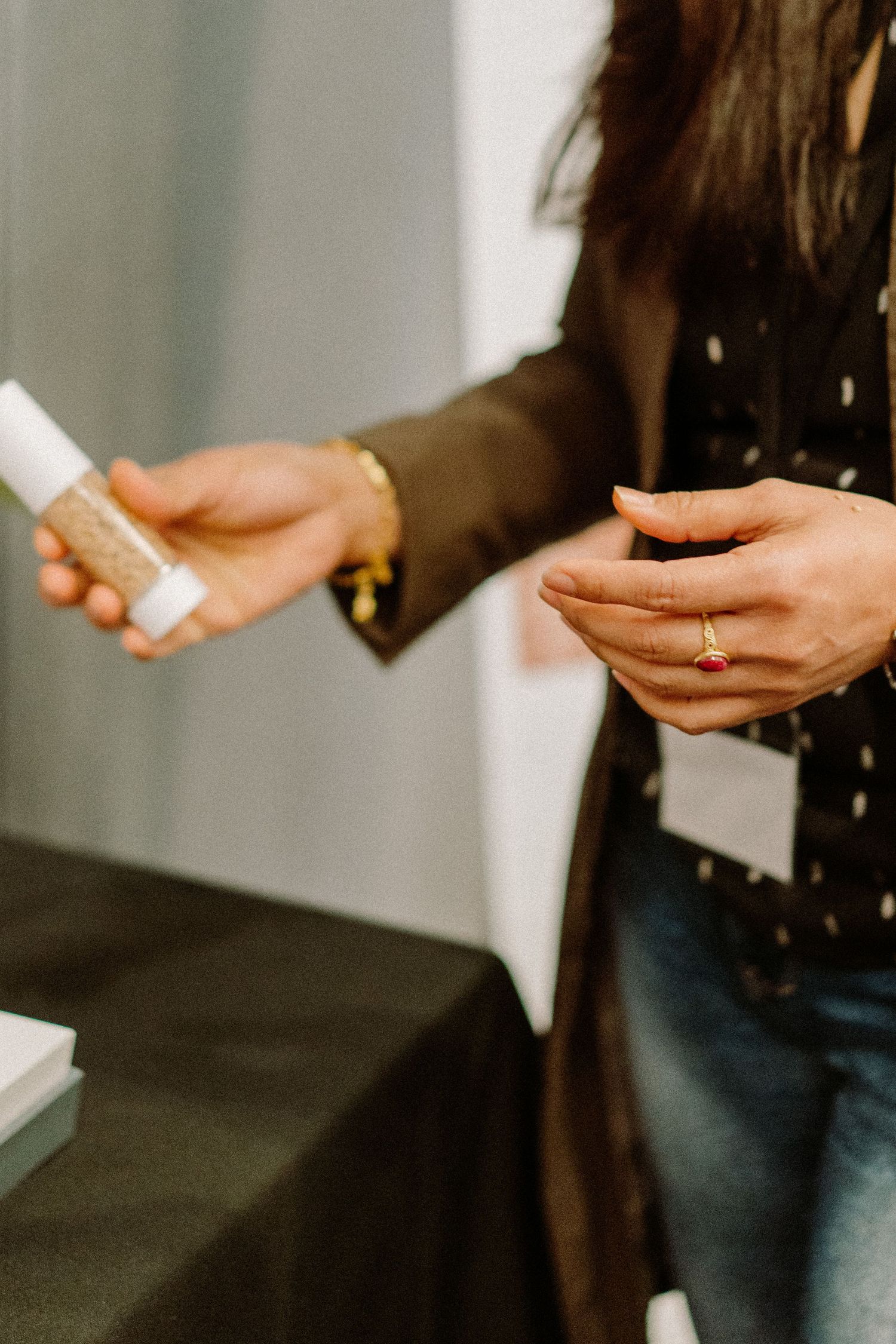 Hands holding and examining beauty product containers at a cosmetics demonstration.
