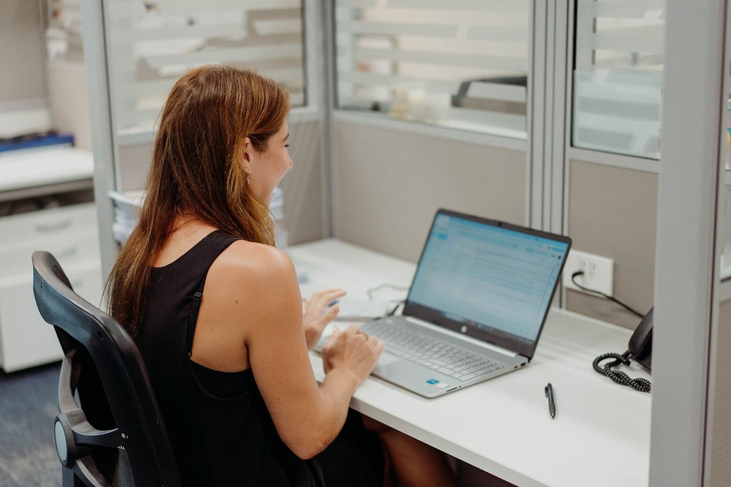 A person working at a desk with a laptop in an office setting with natural lighting.