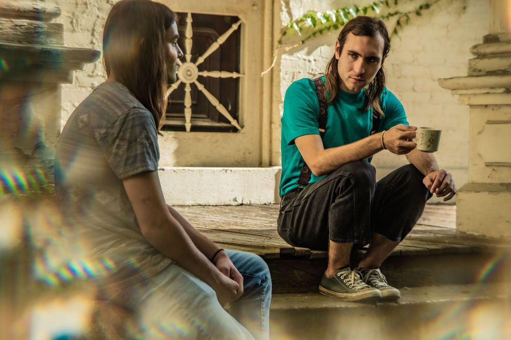 Two people having a casual conversation while sitting on concrete steps outdoors.