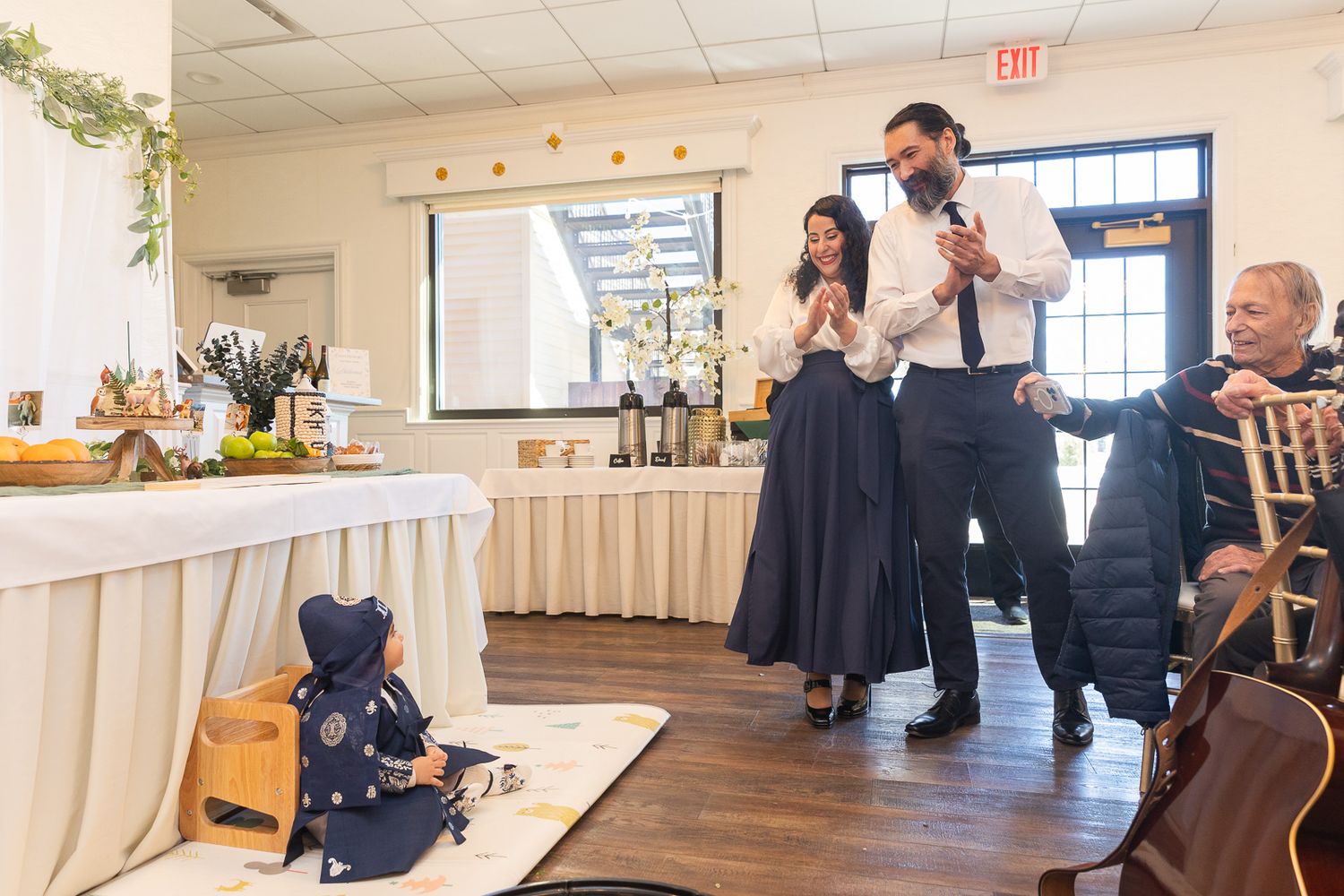 Wedding reception venue with decorated banquet table and guests mingling in an indoor setting.