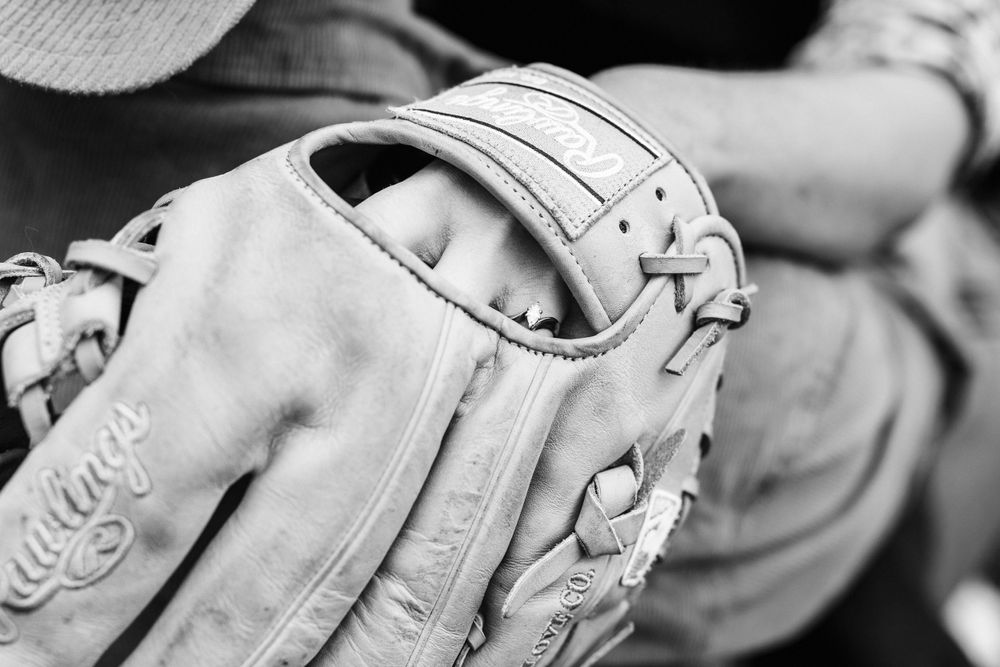 Close-up black and white view of a leather baseball glove with stitching details and webbing pattern.