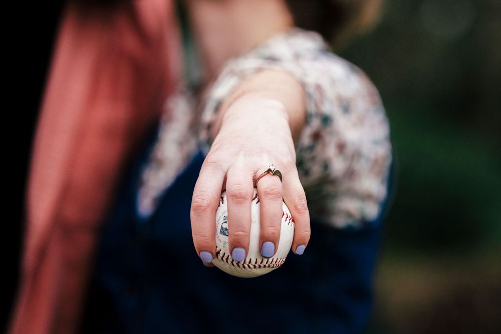 A hand displaying a vintage-style silver ring against a blurred dark background.