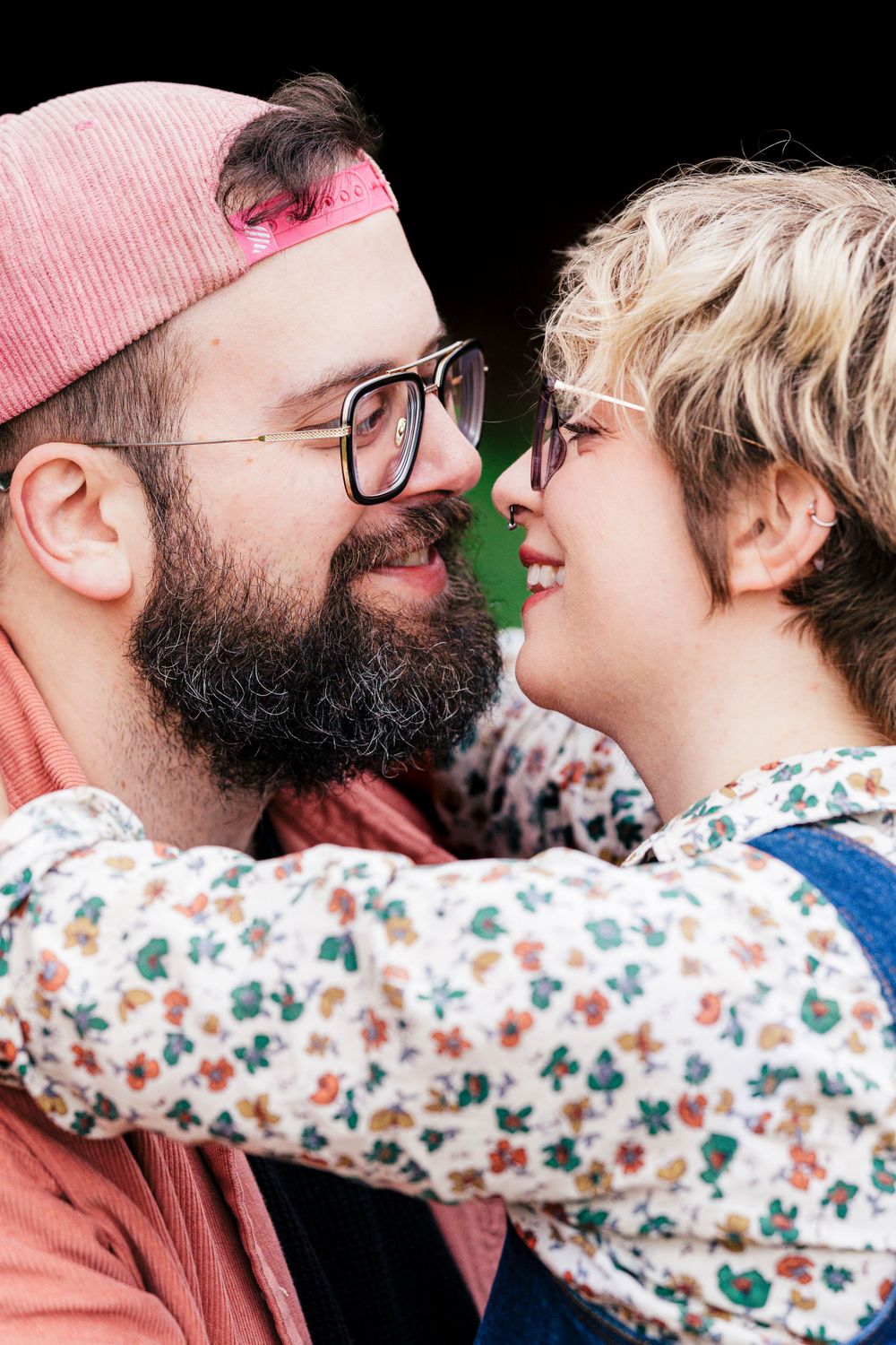 A close intimate portrait showing a couple in a playful loving moment against a black background.