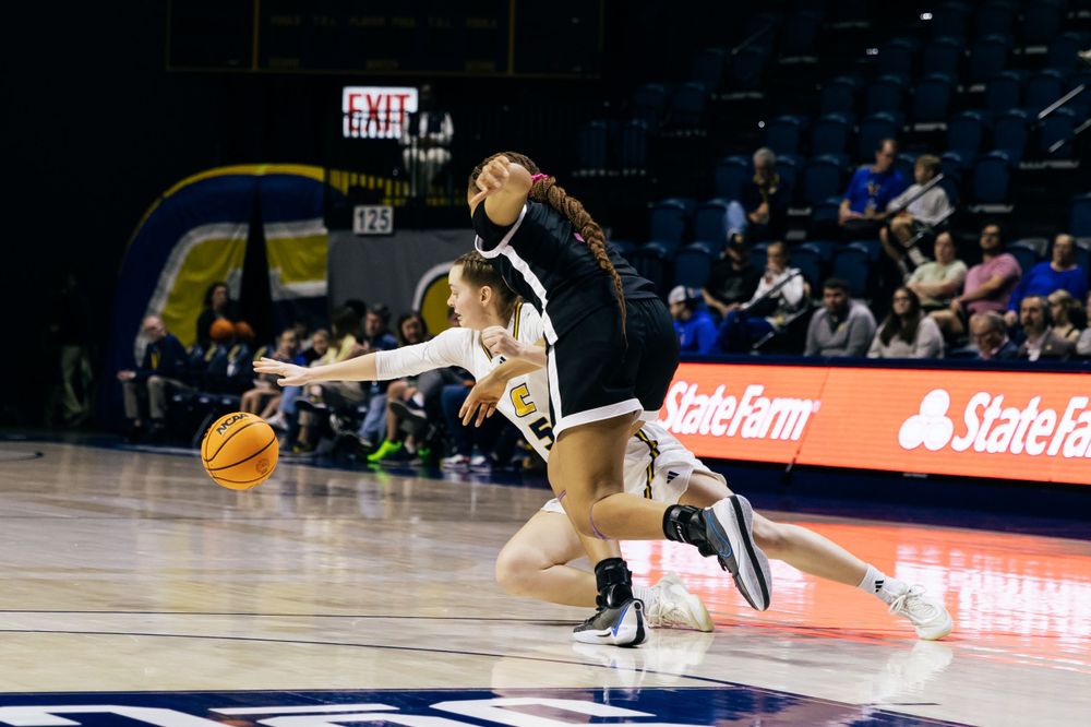 Basketball player dribbles while driving past defender during professional game on indoor court.