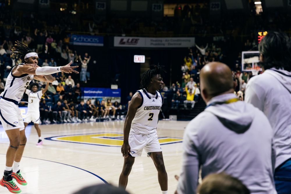 Basketball players in action during an intense indoor game at a packed arena.