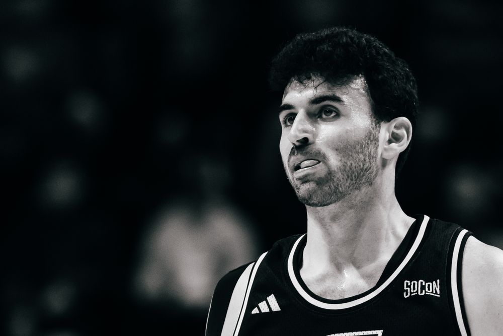 Black and white close-up portrait of a basketball player in an Adidas jersey looking to the side.