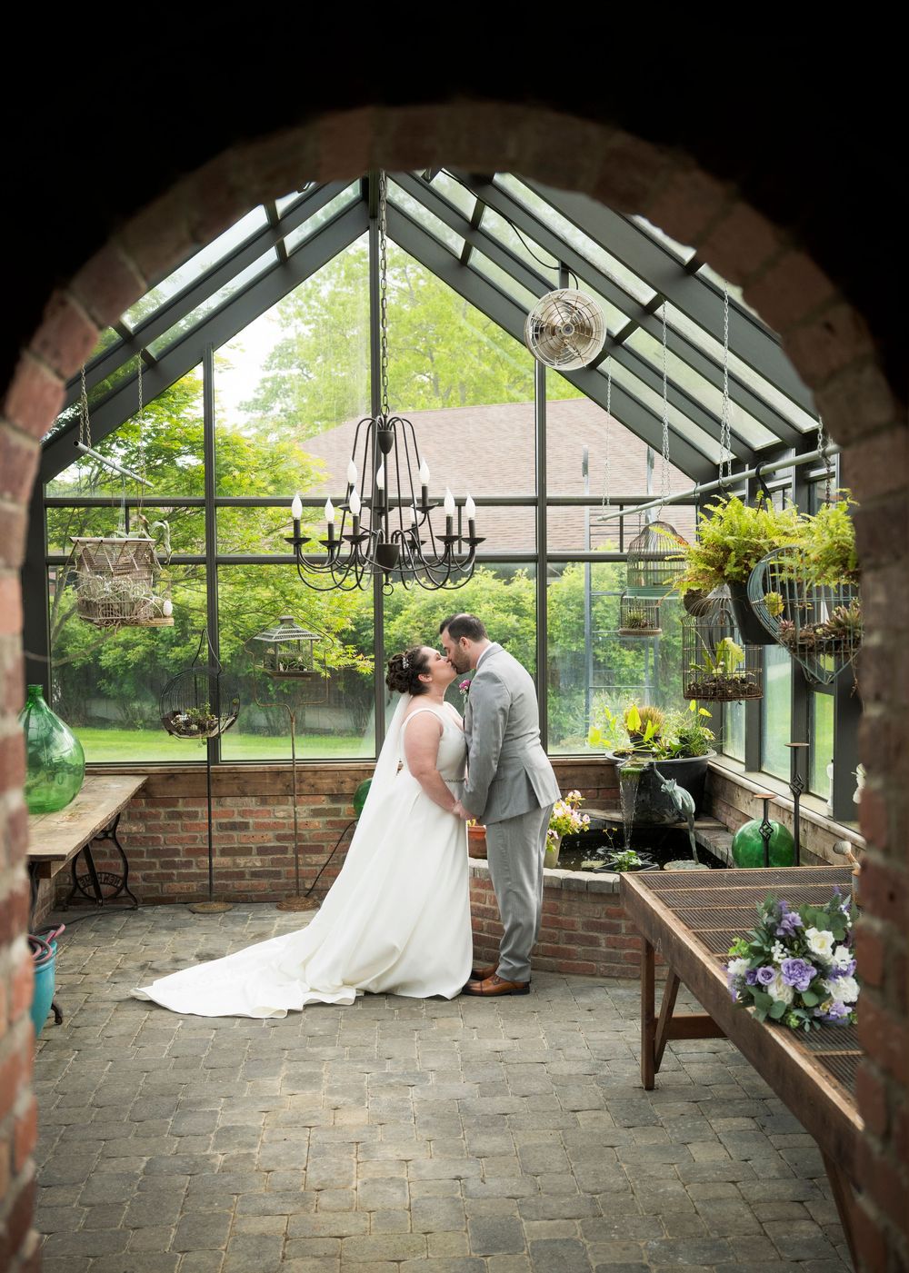 Elegant greenhouse conservatory wedding venue with brick archways and stone flooring.