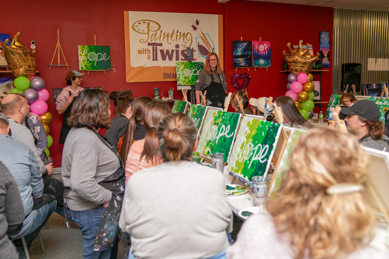 Guests gathered at a painting party event with canvases and supplies at Painting with a Twist studio.