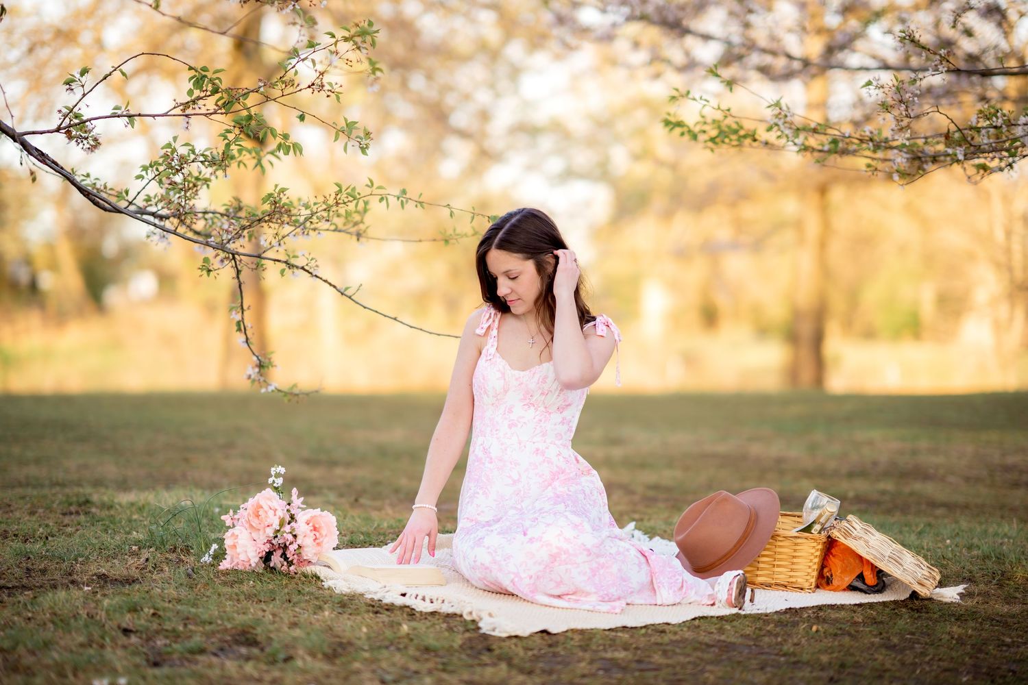 A delicate outdoor scene with a pink dress, spring blossoms, and a picnic blanket in golden afternoon light.