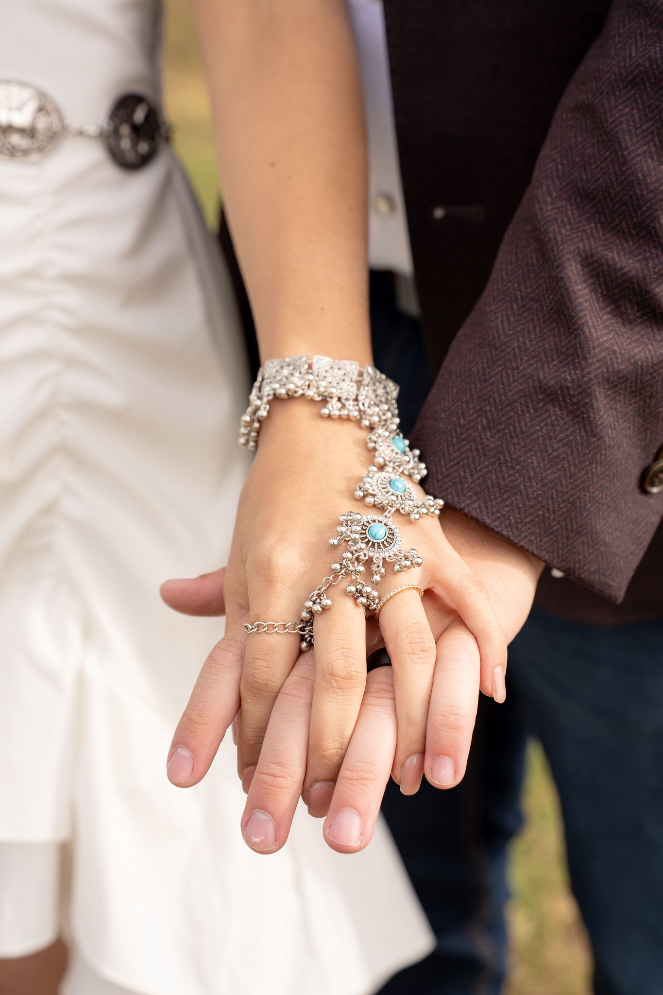 A close-up of hands wearing an ornate silver bracelet ring combo with crystal embellishments.