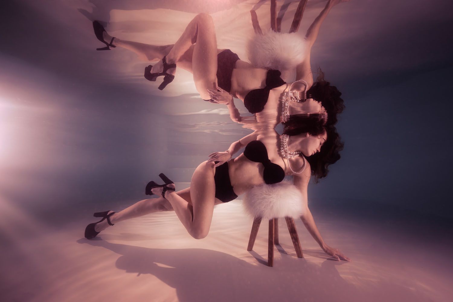 Artistic underwater ballet in rosy pink lighting capturing elegant dancers in ethereal motion.